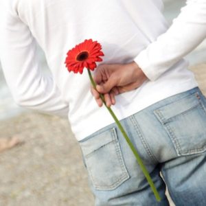 Man with a flower behind his back